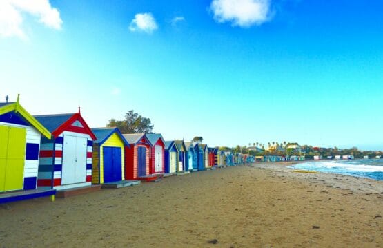 a row of colorful beach huts sitting on top of a sandy beach